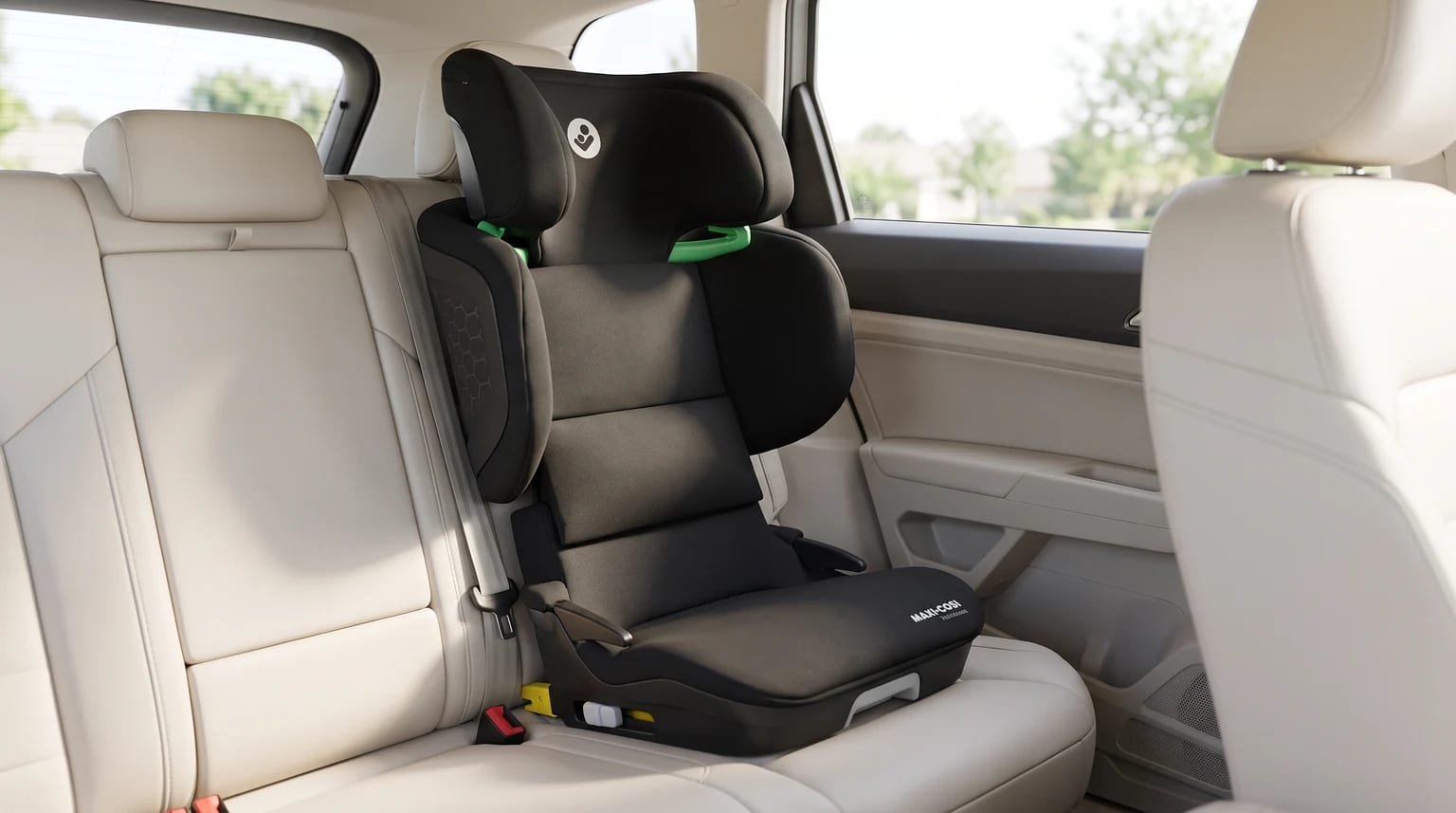 Silla de coche elevadora Maxi-Cosi negra instalada en el asiento trasero de un coche con interior claro.