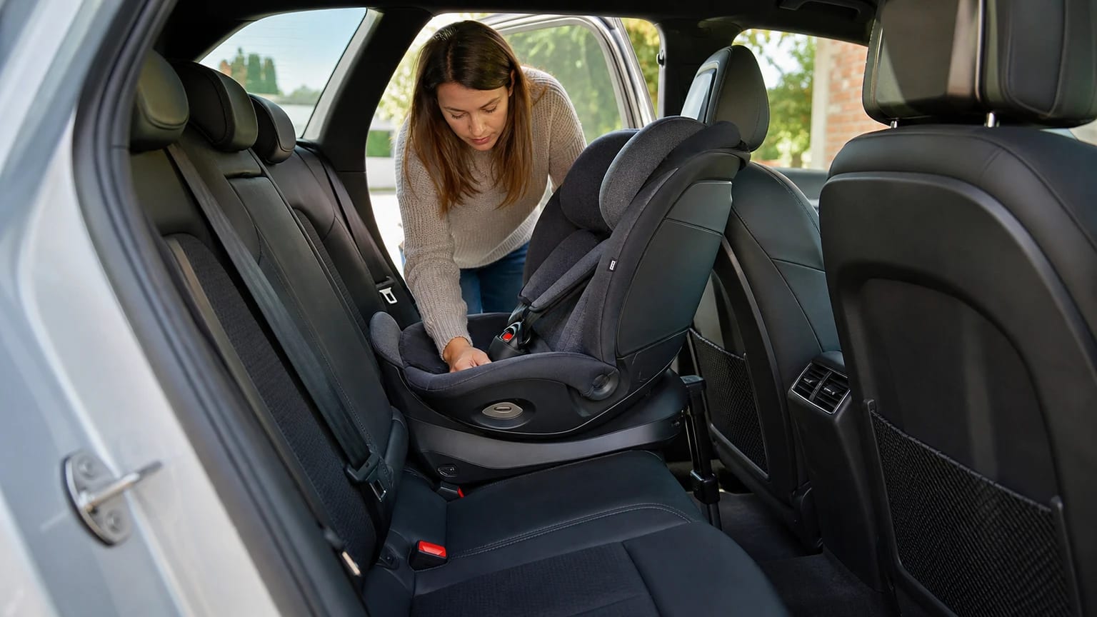 Madre comprobando la instalación de una silla infantil en el asiento trasero del coche