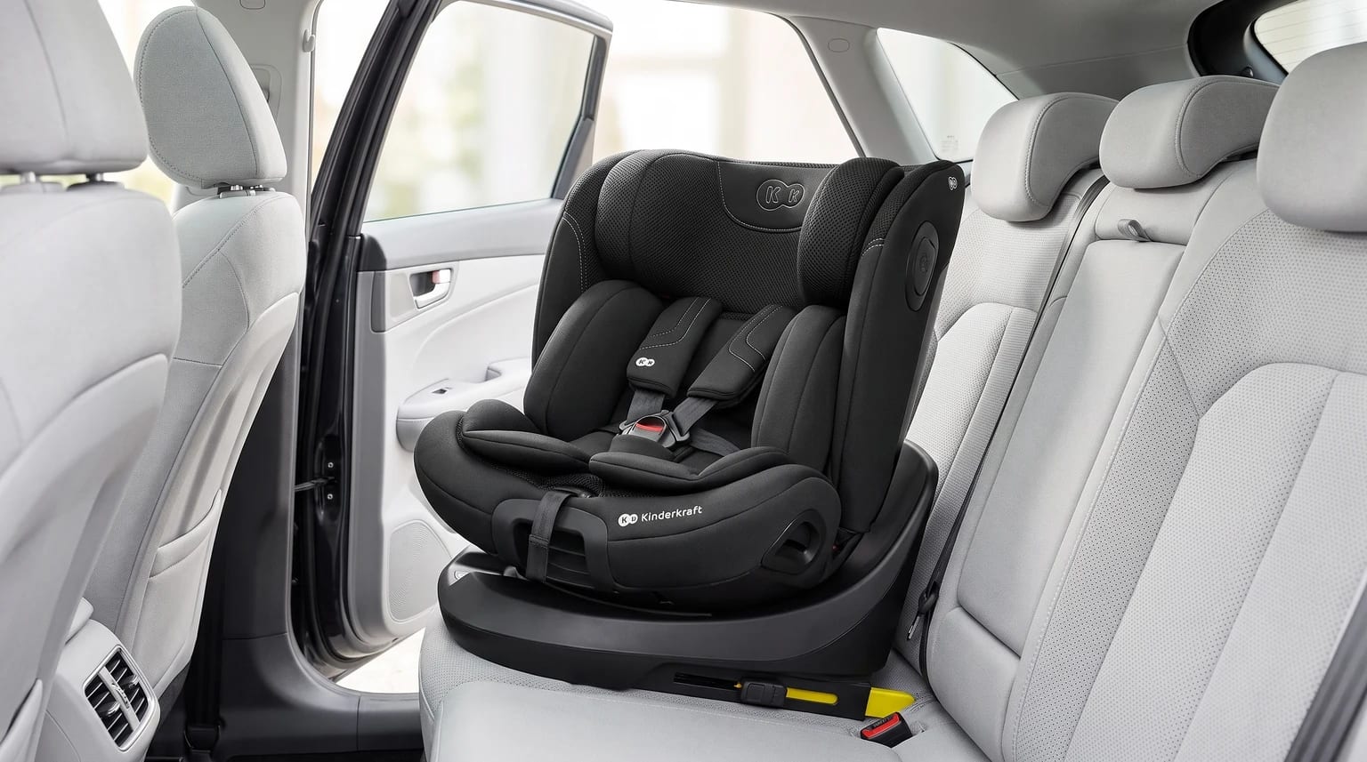 Silla de coche Kinderkraft I-GROW 2 PRO negra instalada en el asiento trasero de un coche con interior gris claro.