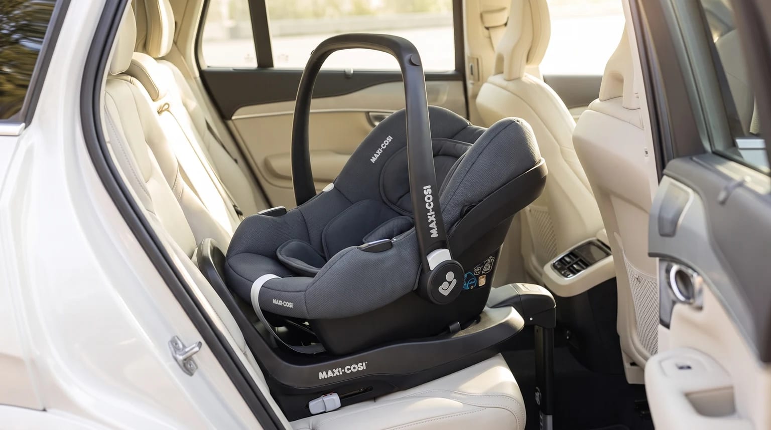 Portabebés Maxi-Cosi CabrioFix gris instalado con base en el asiento trasero de un coche con tapicería clara.