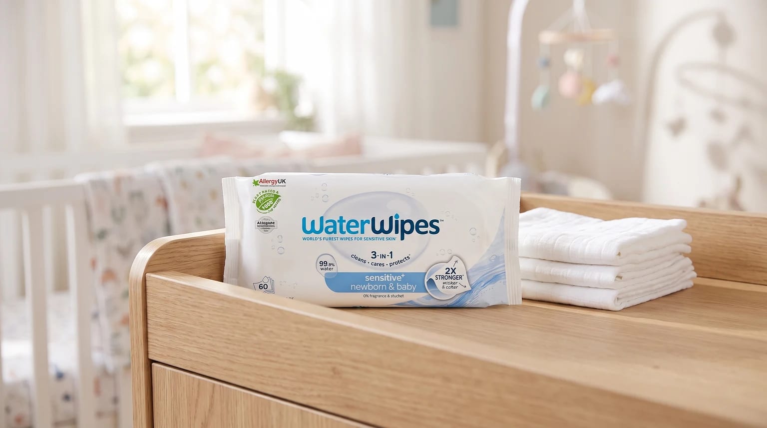 Un paquete de toallitas para bebé WaterWipes sobre un cambiador de madera en una luminosa habitación infantil.