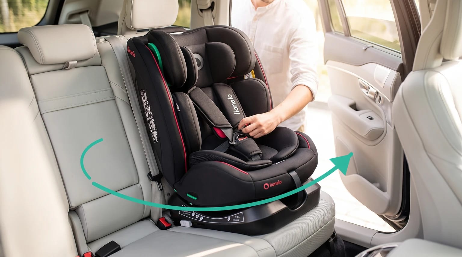Silla de coche Lionelo Aart i-Size negra instalada en el asiento trasero de un coche, con una persona ajustando el arnés y una flecha verde que indica el giro.