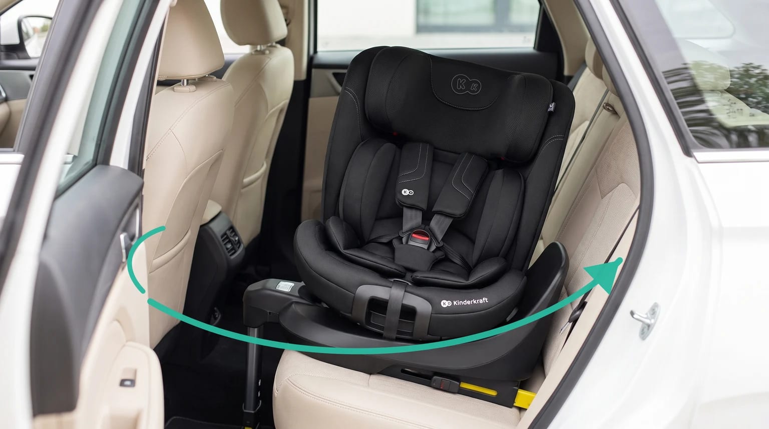 Silla de coche Kinderkraft I-GROW 2 PRO negra instalada en el asiento trasero de un coche con tapicería clara y una flecha verde que indica el giro.